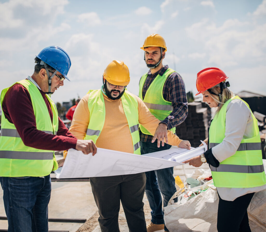 Engineers and architects looking at building blueprint on the building rooftop